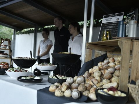 Buffet mit verschiedenen Salaten und Br&ouml;tchen, daneben drei Personen in der Gastronomie, im Hintergrund auf eine Wand blicken.