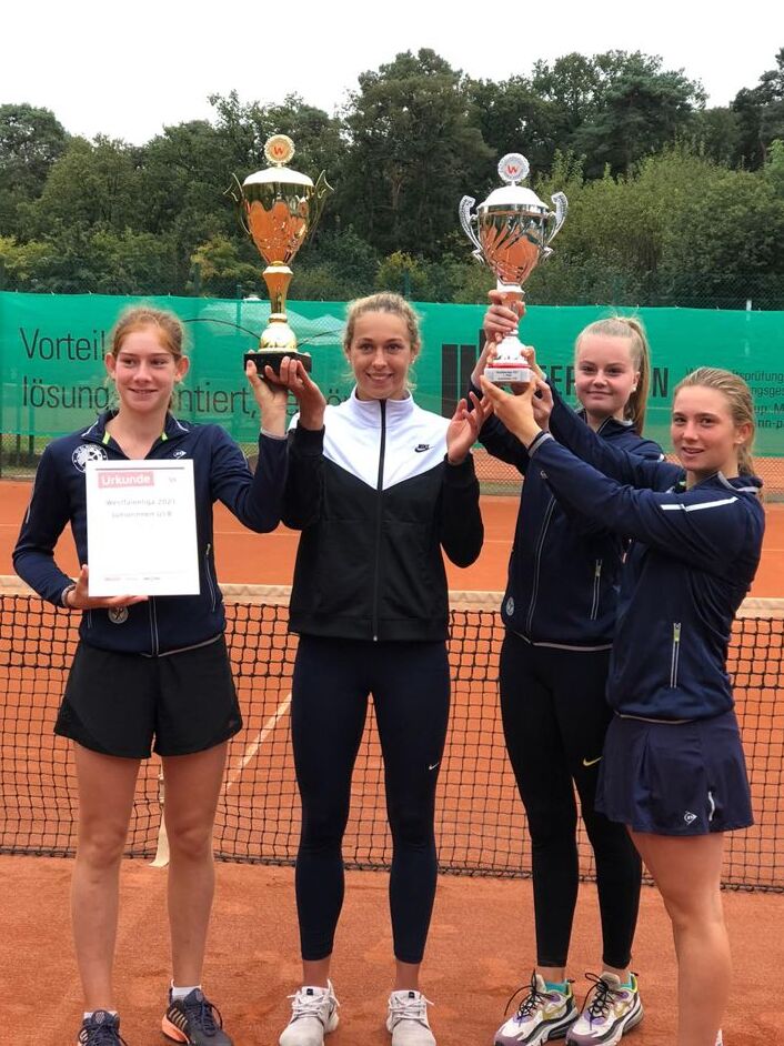 Vier Tennisspielerinnen posieren auf einem Platz, halten Pokale und eine Urkunde nach einem gewonnenen Turnier.