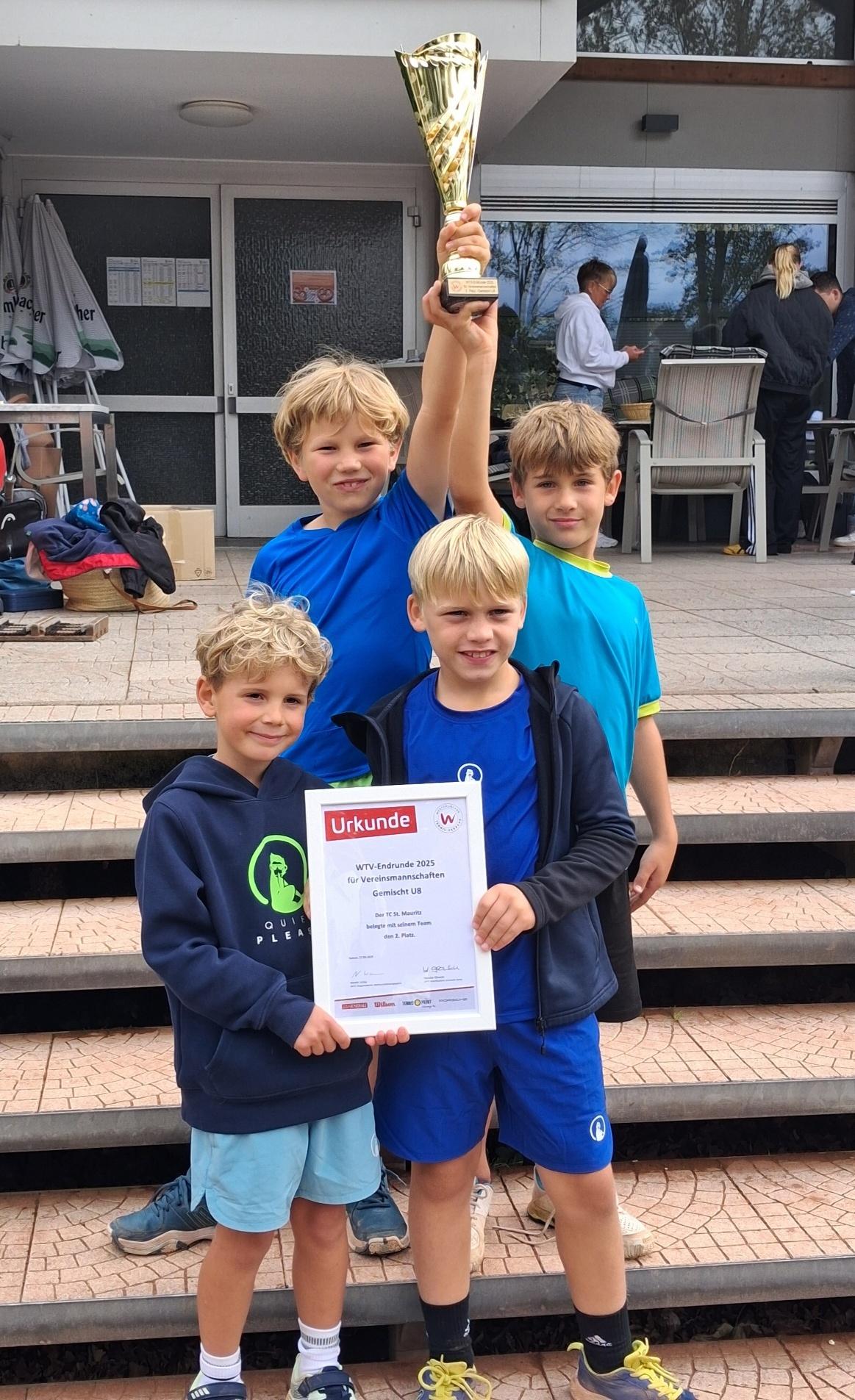 Vier Kinder stehen auf einer Treppe und halten einen Pokal und eine Urkunde in den H&auml;nden.