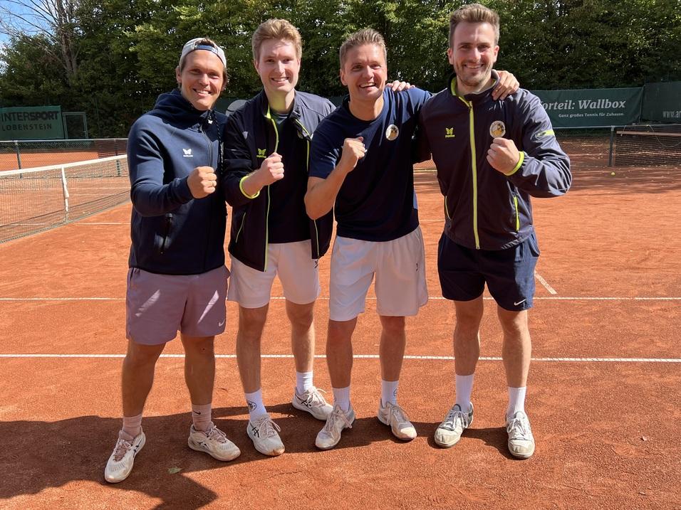Vier Tennis-Spieler posieren l&auml;chelnd auf einem Tennisplatz aus rotem Sand und zeigen ihre F&auml;uste zur Freude.