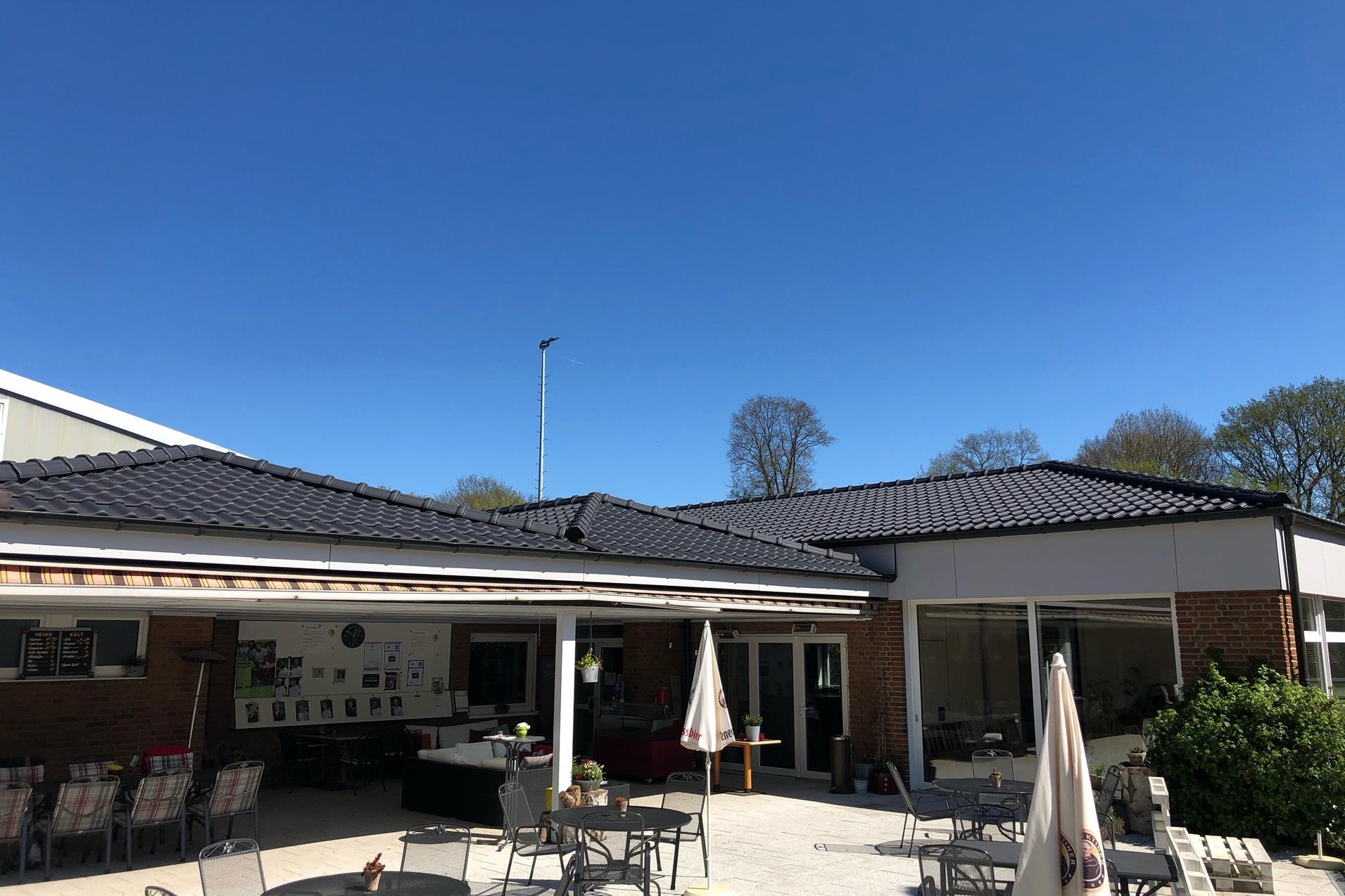 Blick auf ein Caf&eacute; mit Au&szlig;ensitzpl&auml;tzen und klarem blauen Himmel im Hintergrund.