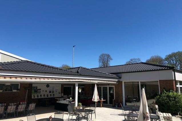 Blick auf ein Caf&eacute; mit Au&szlig;ensitzpl&auml;tzen und klarem blauen Himmel im Hintergrund.