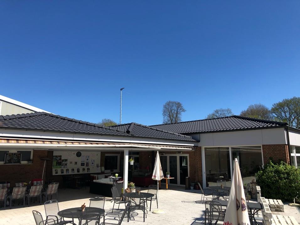 Blick auf ein Café mit Außensitzplätzen und klarem blauen Himmel im Hintergrund.
