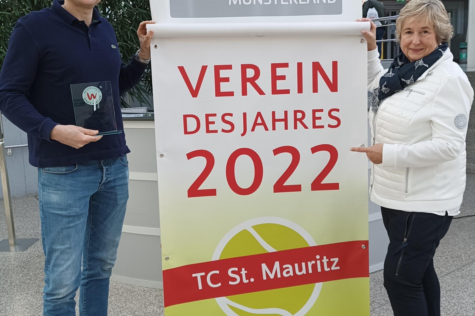 Zwei Personen pr&auml;sentieren ein Banner mit der Aufschrift &bdquo;Verein des Jahres 2022&ldquo; des TC St. Mauritz in einem Foyer.
