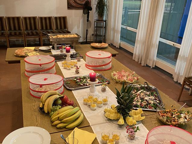 Buffet mit unterschiedlichen Speisen, Obst, Getr&auml;nken und dekorativen Kerzen auf einem langen Tisch.