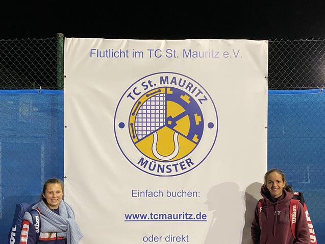 Zwei Tennisspielerinnen stehen neben einem Werbebanner des TC St. Mauritz in M&uuml;nster.